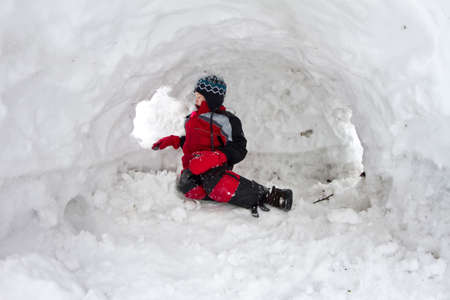 Boy playing in snow fortの写真素材