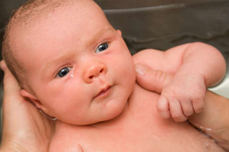 Baby held in bath by handsの写真素材
