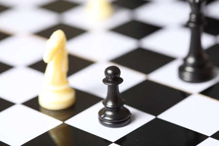 Black Pawn and queen versus white knight Chess Piece with a shallow Depth of Field