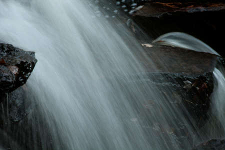 Blurred motion close up of water streaming over rocks at a waterfall in New England, USA