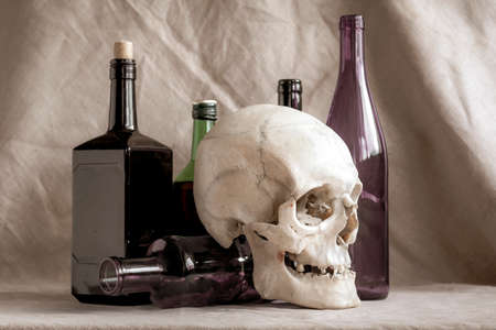 Skull on the background of alcohol bottles. The concept: harm from alcohol; death; alcoholism.の写真素材