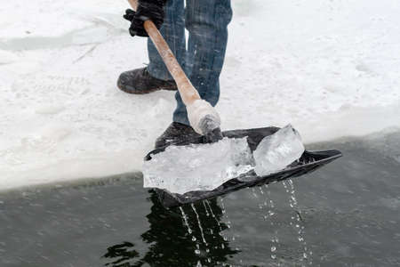 People clear a hole in the ice pond to swim. Winter swimming. Preparing a place for winter swimming.