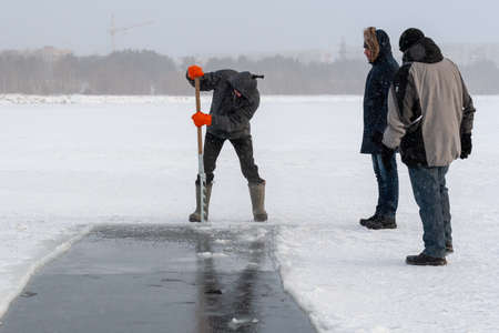 Surgut, Russia, 11 october 2018: People clear a hole in the ice pond to swim. Winter swimming....