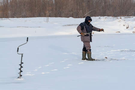 Surgut, Russia, 11 october 2018: Fisherman catches fish in the winter on the ice.のeditorial素材