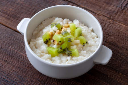 Vegetarian breakfast: Rice milk porridge with banana, pear and kiwi slices.の写真素材