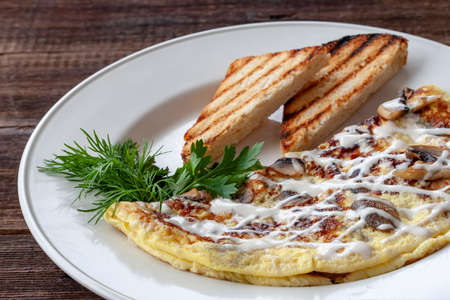 Vegetarian breakfast: scrambled eggs with mushrooms, greens and croutons on a white plate.の写真素材