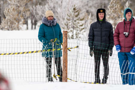 Russkinskaya, Surgut, Russia, 03/23/2019: open traditional holiday of reindeer herders and fishermen, indigenous peoples of Siberia. Spectators watch the competition from behind the fence.のeditorial素材