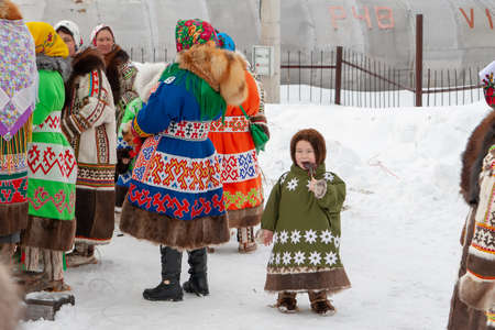 Russkinskaya, Surgut, Russia, 03/23/2019: open traditional holiday of reindeer herders and fishermen, indigenous peoples of Siberia. A woman is a local aboriginal with a child in national costumes.のeditorial素材