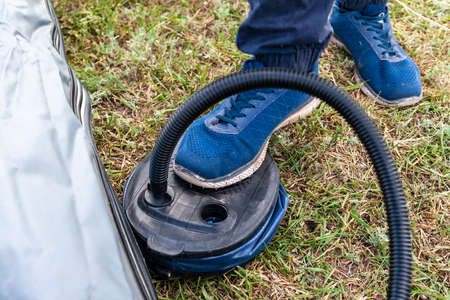 Inflatable boat pumping process, close-up. A fisherman pumps an inflatable boat with a foot pump.の写真素材