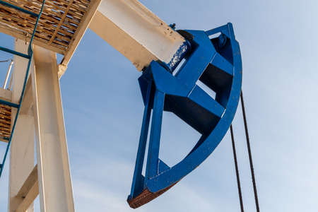 Detail of the oil pump against the blue sky. Brightly colored oil pumps produce oil or gas.