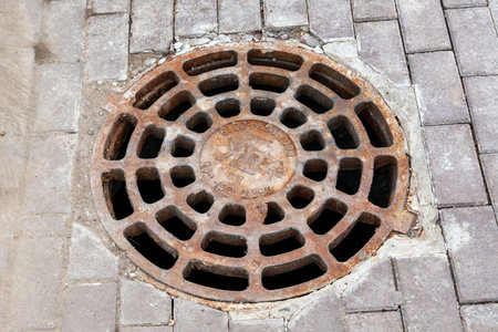 Kungur, Russia, 07.22.2021 Storm sewer hatch. Old rusty sewer manhole on the street of the city of Kungur.のeditorial素材