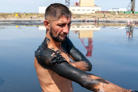 A man smears his shoulders with healing mud. Salty, mud medicinal lakes of Sol-Iletsk.