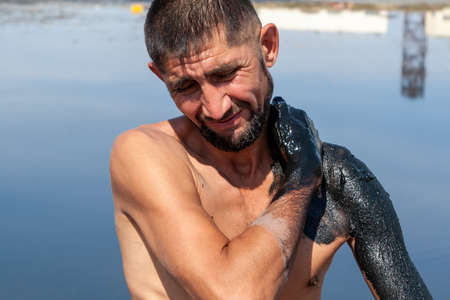 Salty, mud medicinal lakes of Sol-Iletsk. A man smears his body with healing mud.