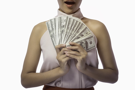 Portrait of a young Asian woman hands counting a wad of banknotes, many US dollars, Isolated on a...