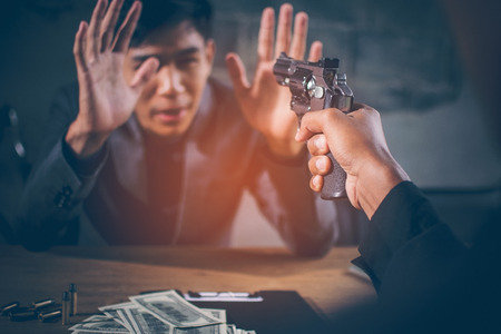 Criminals are aiming at young businessman. Dollar banknotes USD and bullets on the table, The young...