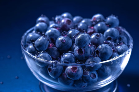 Fresh blueberries in a glass bowl with water droplets. Conceptual illustration created with generative AIの素材