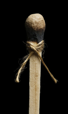 Wooden matchsticks tied with rope isolated on a black background.の素材