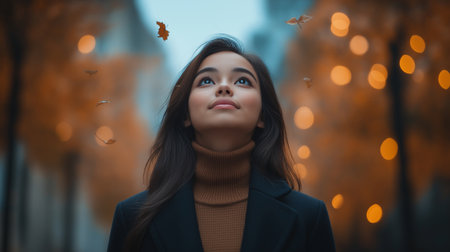 Portrait of a beautiful brunette woman in a blue coat on a background of autumn trees.の素材