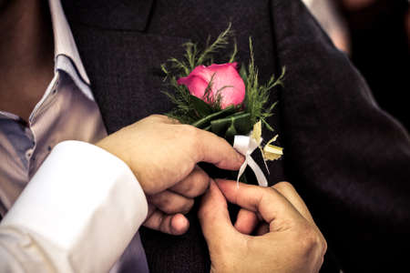 Pinning the Groom with boutonniere flowers before wedding ceremonyの写真素材