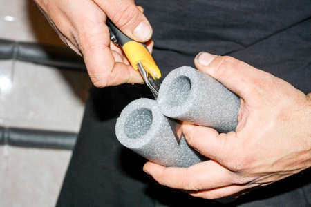 Worker cuts the foam insulation for pipesの写真素材