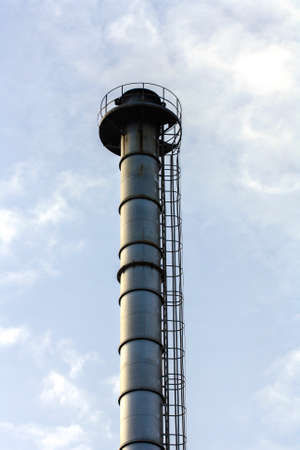 Factory metallic chimney with a background of blue sky