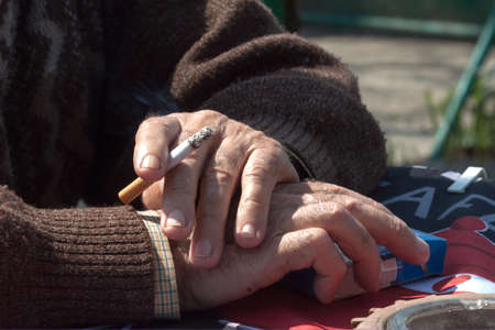 Old man hand holding a burning cigaretteの写真素材