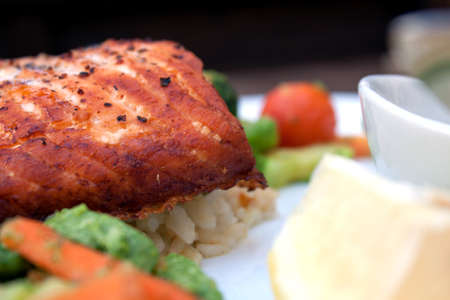 A white plate with a healthy portion of salmon and salad.