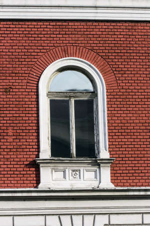Old wooden window on the facade of red brickの写真素材