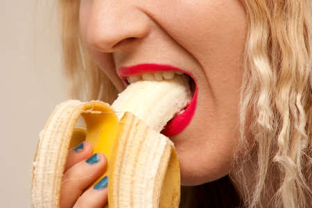 Beautiful young woman eating an bananaの写真素材