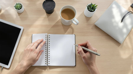 top view of woman writing in notepad with cup of coffee on tableの素材