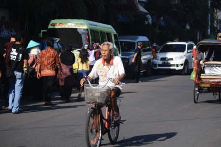 Yogyakarta, Indonesia - April 21 2013. Old man who is cycling under the hot sun during the dayのeditorial素材