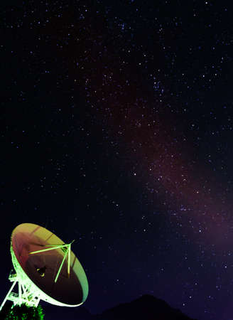 Satellite dish under the starry sky of the Milky Way, vertical night image.