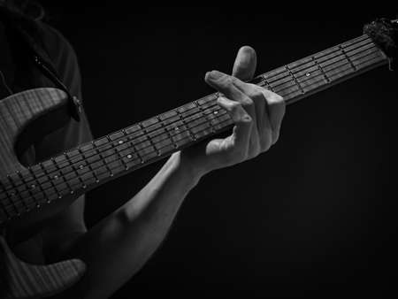detail of hand playing an electric guitar, black and white imageの写真素材