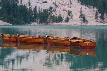 Row of wooden boats tied up in the middle of Lake Braies at first light in the morning, Trentino Alto Adigeの写真素材