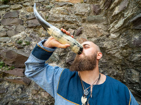 Portrait of a young warrior drinking from a Viking horn, outdoor settingの写真素材