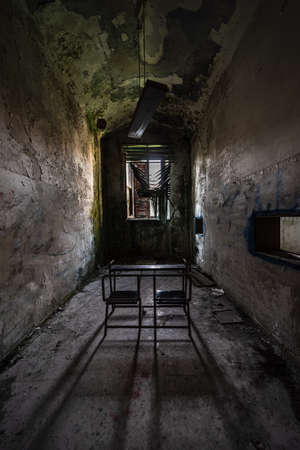 A school desk in a narrow classroom of an abandoned and decadent asylum, urbex image