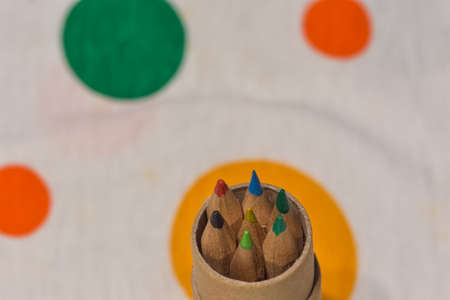 Colored pencils inserted in a cardboard cylinder on a colored plane, horizontal image