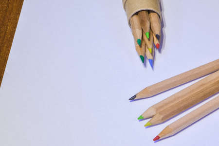 Colored pencils resting on white sheet, horizontal image