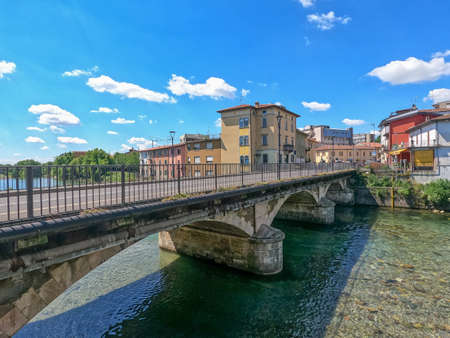 View of a bridge over the river on a sunny day with a blue sky and white cloudsの写真素材