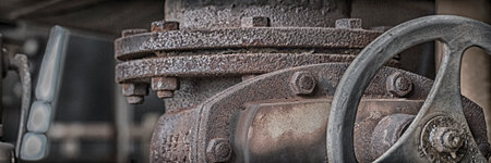 a close up of an old rusty valve in a decommissioned industrial plant