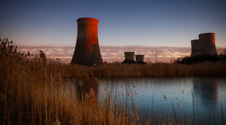 a small pond of a nature reserve is located here in front of an old cooling tower of a disused coal-fired power plant. Photographed at sunsetの写真素材