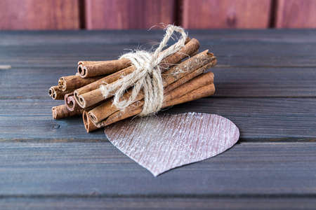 Cinnamon sticks with silver heart decorated with cloth pin and red sparkling stars on wooden planks St.Valentine's Day toned selective focusの写真素材