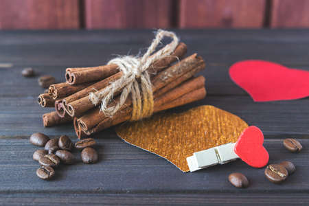 Cinnamon sticks with roasted coffee beans decorated with hearts and cloth pin on wooden planks St.Valentine's toned selective focusの写真素材