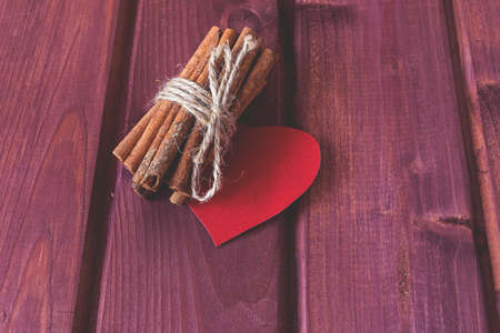 Cinnamon stocks with heart on wooden planks toned selective focusの写真素材