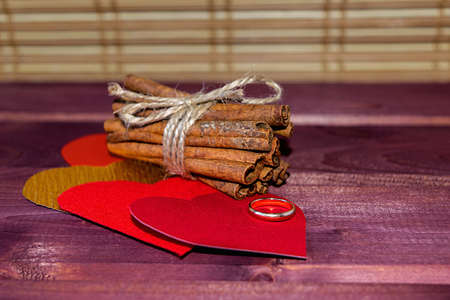 Hearts with cinnamon sticks and wedding ring on wood toned selective focusの写真素材