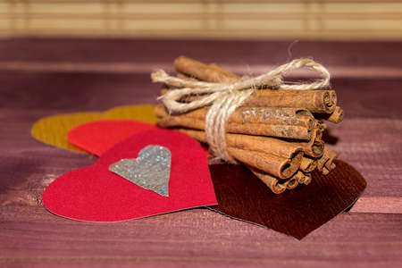 Hearts with cinnamon sticks and wedding ring on wood toned selective focusの写真素材