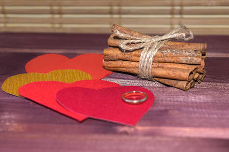 Hearts with cinnamon sticks and wedding ring on wood toned selective focusの写真素材