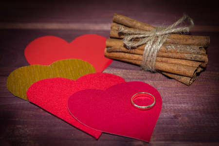 Hearts with cinnamon sticks and wedding ring on wood toned selective focusの写真素材