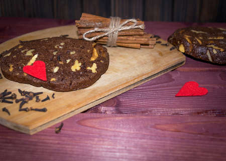 Walnut chocolate cookies with cinnamon sticks on wooden planks background toned selective focusの写真素材