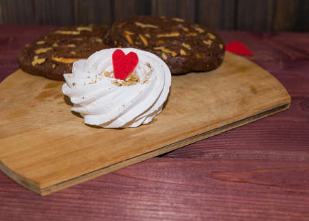 Single meringue decorated with heart and chocolate biscuits toned selective focusの写真素材